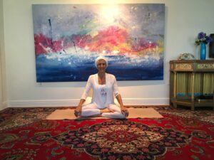 A woman sitting cross legged on a yoga rug.